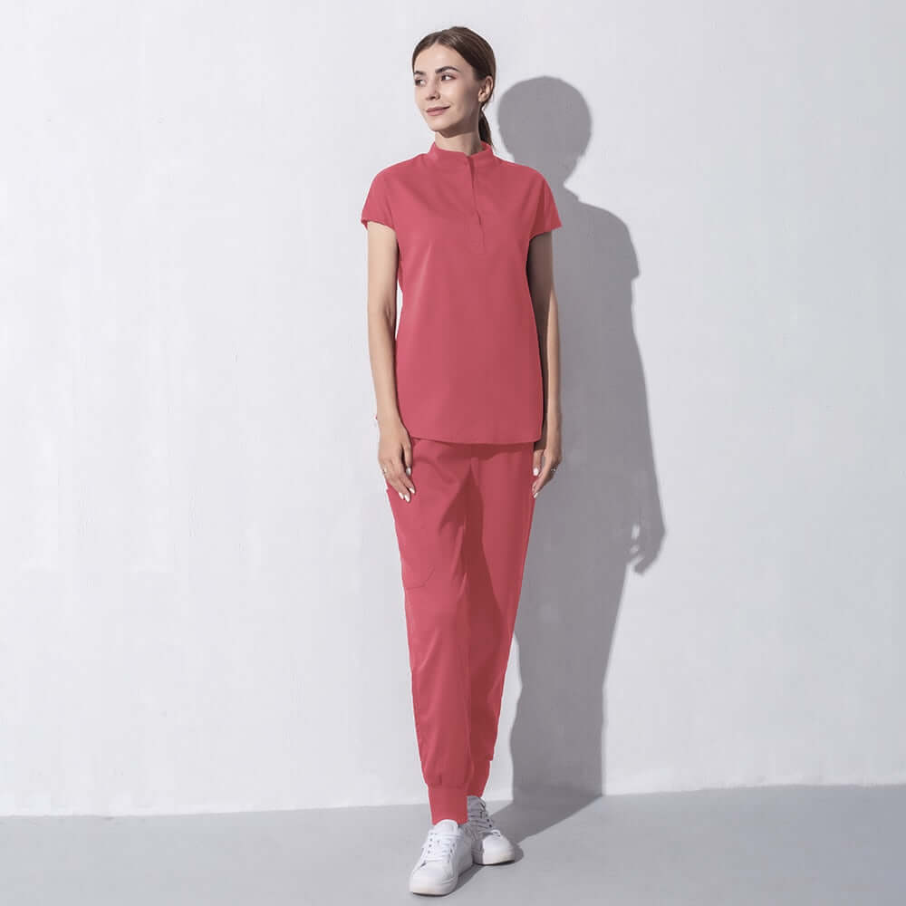 Woman in fashionable red salon workwear standing against white background, featuring stylish and professional design ideal for beauty aesthetics.